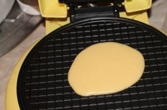 1. Этап. Вафельная трубочка с халвой: Смажьте вафельницу сливочным маслом. Из одной столовой ложки теста получится одна вафля. Выливайте порционно тесто и закрывайте крышкой. Готовность вафель зависит от вашего аппарата (от 2 до 7 минут).