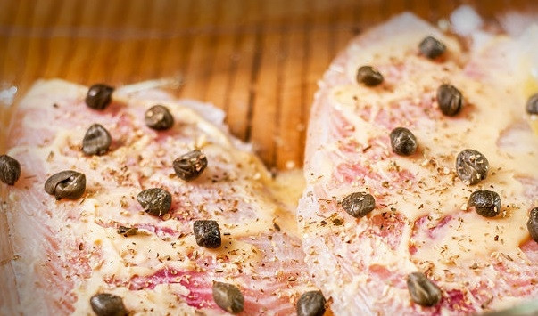 1. Этап. Филе тилапии в духовке: 3. Посыпьте филе тилапии орегано, солью и перцем по вкусу и выложите каперсы.