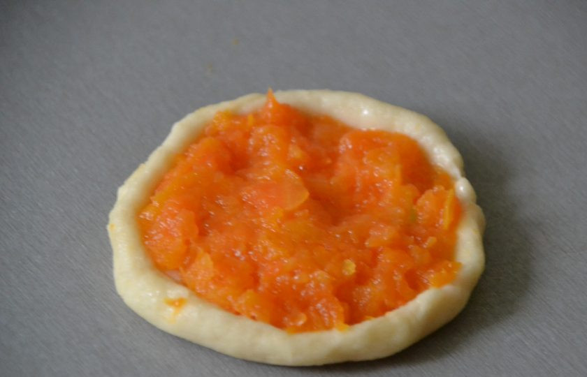 1. Этап. Морковные шаньги: Раскатывайте тесто в лепешку, мука на этом этапе не требуется, так как тесто совсем не липнет к столу. В центр лепешки положите начинку, немного поднимите бортики.