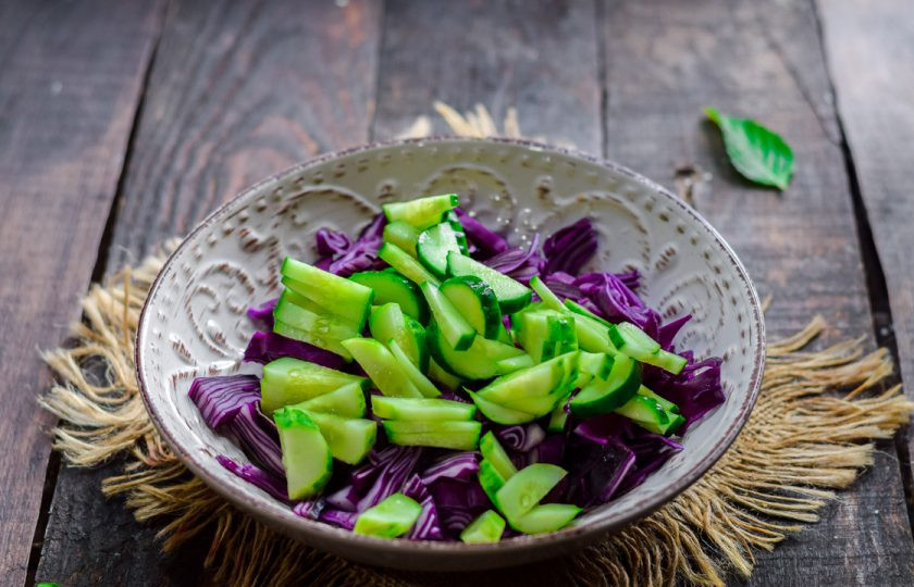 1. Этап. Салат с красной капустой и кукурузой: Огурец сполосните и просушите. Нарежьте огурец полосками и добавьте в миску к капусте.