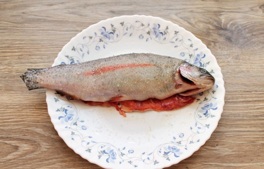 1. Этап. Радужная форель в духовке с овощами: Форель очистите от чешуи и внутренностей. Удалите жабры и промойте. Обсушите рыбу, смажьте маслом и посолите снаружи и внутри.