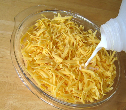 1. Этап. Сырный соус в микроволновке: 3. Сыр выложите в приготовленную мисочку, залейте его молоком, чтобы немного покрыл сырную массу.