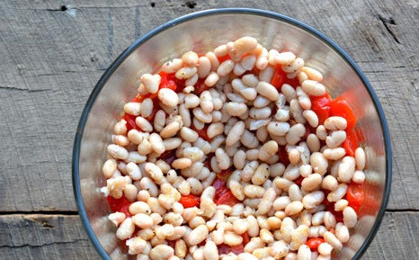 1. Этап. Слоеный салат Праздничный: 4. Консервированную белую фасоль откиньте на дуршлаг, затем выложите на помидоры черри. Четвертый слой салата 