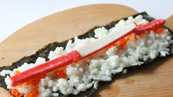 1. Этап. Роллы с красной икрой: Сверху кладем несколько полосочек нарезанной вдоль крабовой палочки.