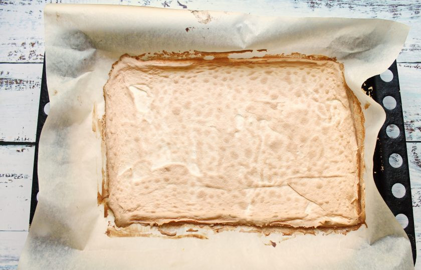 1. Этап. Меренговый рулет с мандаринами: Выпекайте меренговый корж в течение 20-25 минут. Верх должен стать золотистым и хрустящим. Спустя время достаньте корж из духовки и переверните его на чистый лист пергамента, снимите пергамент, на котором выпекался. Полностью остудите меренговый корж.