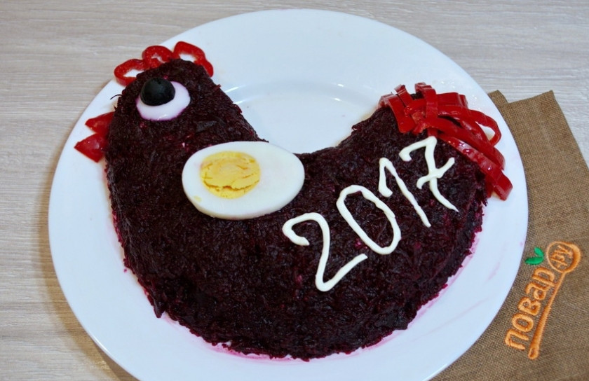 1. Этап. Салат Петух на Новый год: Из отваренного вкрутую куриного яйца изобразите крылышко петушка. Майонезом нанесите надпись. Из помидора или болгарского перца изобразите клювик, гребешок и хвост петуха.