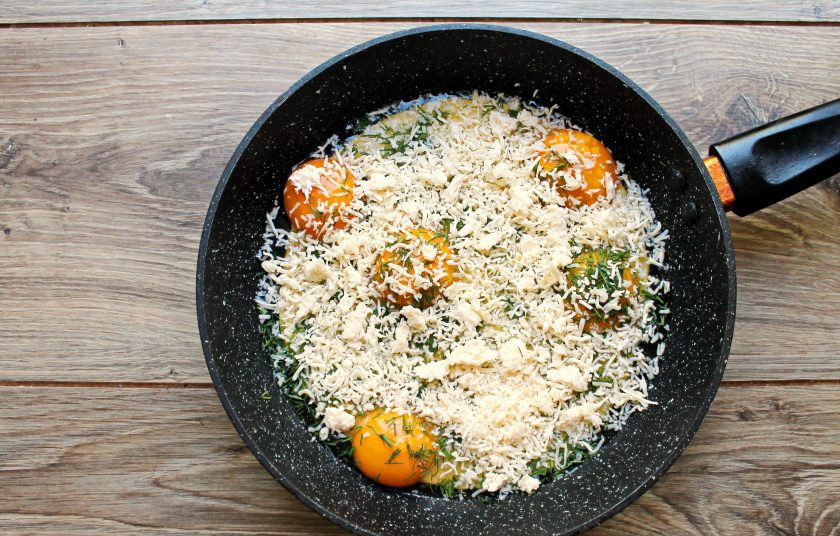 1. Этап. Яичница в лаваше Волшебный завтрак: Сыр натрите на средней терке и половиной посыпьте яйца с укропом.