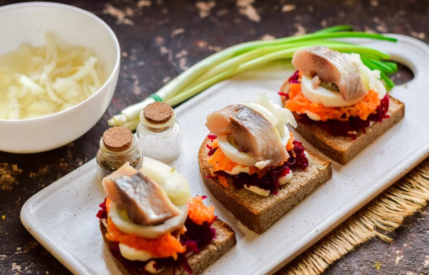 1. Этап. Бутерброды Сельдь под шубой: Завершающий акцент - выложите по кусочку селедки на яйцо, добавьте немного маринованного лука. Бутерброды можно подавать к столу.