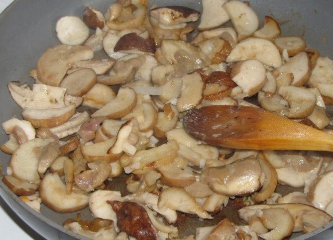 1. Этап. Свинина в горшочке с грибами: 4. Верните сковороду, где обжаривали мясо на огонь, влейте растительное масло и грибы, обжаривайте 5-7 минут, а в самом конце добавьте измельченный чеснок. Выложите грибы в горшочки поверх мяса.