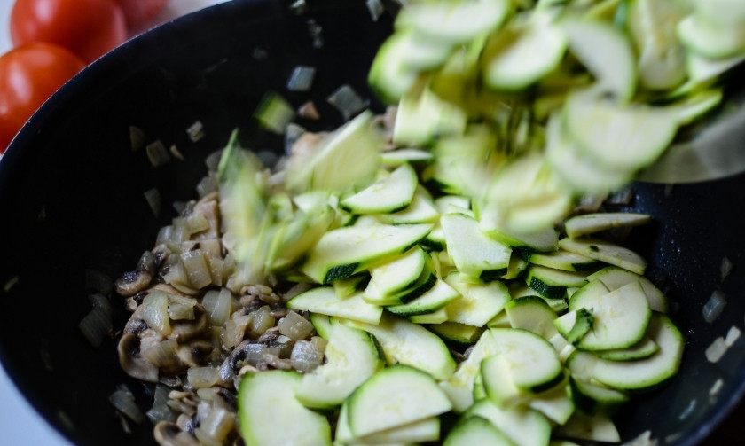 1. Этап. Тушеные овощи с сыром: Нарежьте цукини полукольцами и выложите к луку и шампиньонам.