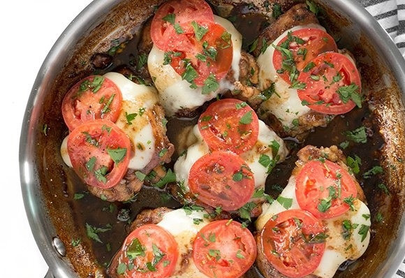 1. Этап. Куриные бедра с сыром и томатами: 7. Накройте сковороду крышкой, чтобы сыр расплавился. Нарежьте мелко зелень и украсьте ей мясо.