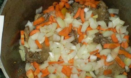 1. Этап. Утка, тушенная с овощами: Морковь и репчатый лук нарежьте кубиками. Закиньте их к мясу. Продолжайте жарить под крышкой.