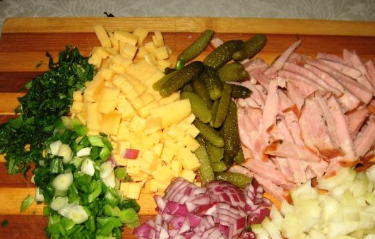 1. Этап. Салат с твердым сыром: Соломкой режем огурцы и колбасу. Сыр нарезаем кубиками, а зелень измельчаем. Смешиваем все в глубокой тарелке.