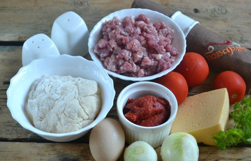 1. Этап. Каннеллони с фаршем под томатным соусом: Подготовьте все необходимые ингредиенты. Луковицы очистите от шелухи, помидоры промойте. Заранее приготовьте тесто. Для этого смешайте муку с солью, разбейте яйцо и хорошенько размешайте его. Влейте воду и замесите мягкое тесто.