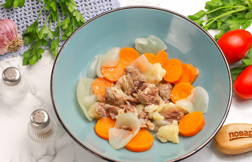 1. Этап. Холодец на костях: Извлеките косточки из бульона, срежьте с них мясо и выложите в глубокую тарелку. Нарежьте отварные овощи и добавьте туда же. Бульон процедите через ситечко.