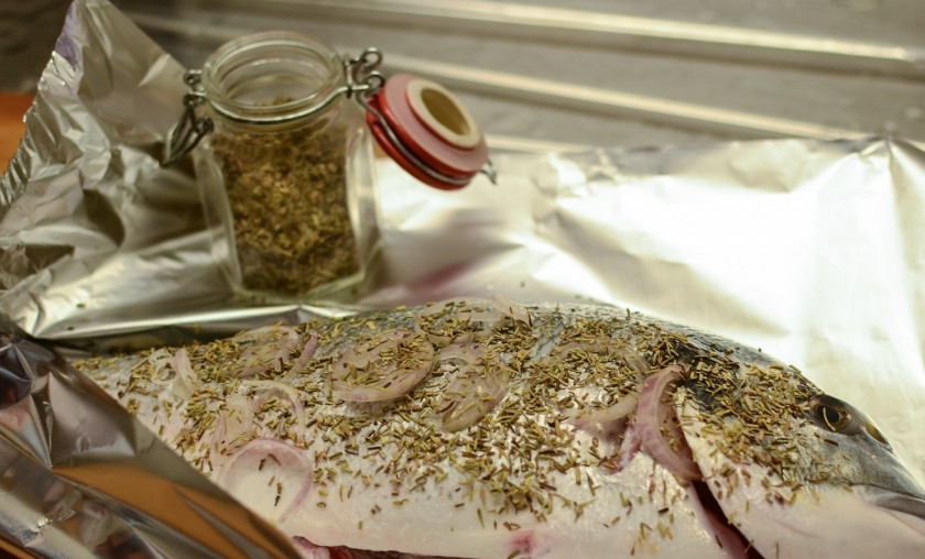 1. Этап. Дорада в духовке в фольге: Приготовьте рыбу. Помойте и разрежьте ей брюшко и уложите в него лук, сверху рыбы. Посыпьте приправами.