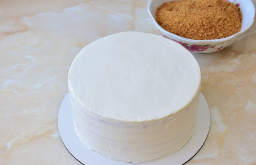 1. Этап. Медовик с клубникой и сметанным кремом: Пропитанный торт освободите от упаковки. Обмажьте бока и верх кремом. Добавлять много крема и тщательно обмазывать не надо. Достаточно лишь, чтобы было где обсыпать крошкой.