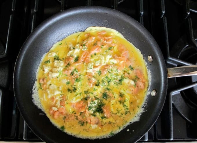 1. Этап. Скрэмбл с лососем: 4. Теперь влейте яйца, добавьте сыр кусочками и мелко нарезанный укроп.