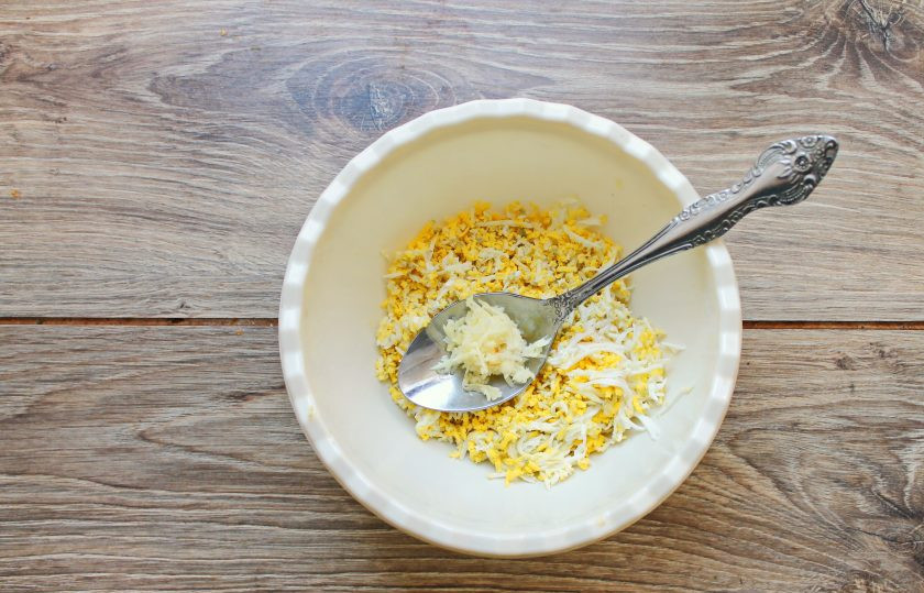 1. Этап. Закусочные конфеты: Чеснок измельчите и добавьте к яйцам.