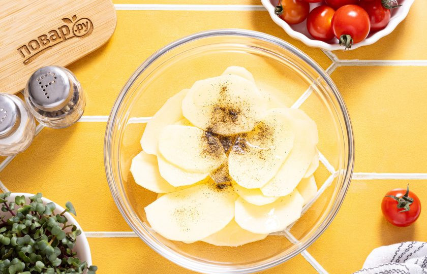 1. Этап. Чипсы из картошки в аэрогриле: Переложите нарезанный картофель в глубокую миску, влейте растительное масло, добавьте соль и черный молотый перец. Перемешайте.