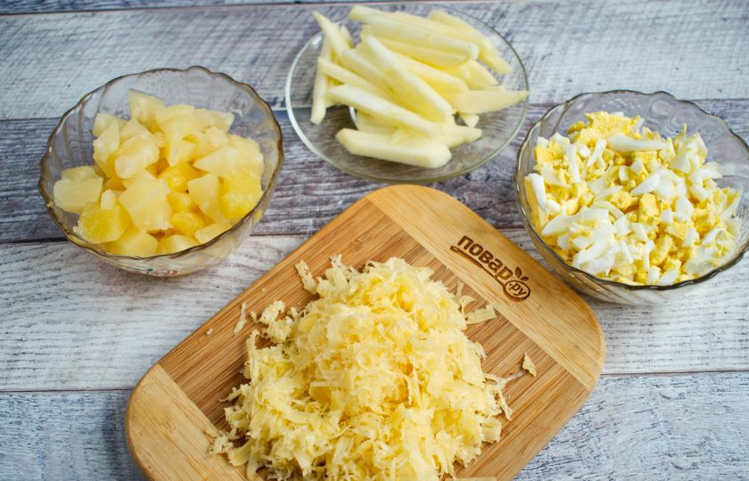 1. Этап. Салат Снежный: Сыр натрите на мелкой терке. Ананас нарежьте мелкими кубиками. Яблоко очистите, нарежьте тонкими брусочками. Яйца очистите, нарежьте соломкой. Чеснок пропустите через чесночный пресс, соедините с майонезом.