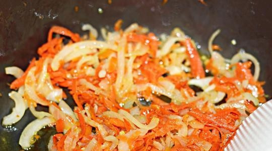 1. Этап. Желудки куриные, тушенные в сливках: Почистите, помойте и натрите морковь. Добавьте её к луку. Перемешайте и готовьте пару минут.