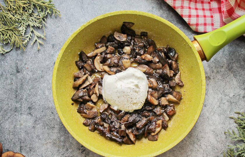 1. Этап. Грибы по-деревенски: Добавьте к грибам сметану, все посолите, поперчите и перемешайте. Тушите грибы на среднем огне в течение 3-4 минут, перемешивая.