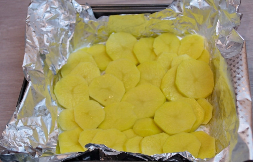 1. Этап. Скумбрия кусочками в духовке: Сырой картофель очистите от шкурки и нарежьте небольшими кусочками. Чем тоньше, тем лучше. Уложите кружочки картофеля на лист фольги. Посолите, поперчите, полейте растительным маслом.