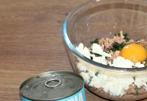 1. Этап. Блинные корзиночки с начинкой из тунца: 9. Приготовим начинку. Выкладываем тунец без жидкости в миску. Если тунец кусочками, то разминаем его вилкой, но не мельчим. Добавляем 1 яйцо, измельченную и протертую руками зелень укропа. Крошим рассольный сыр и перемешиваем.