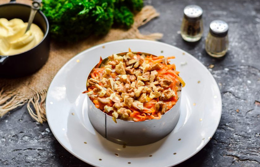 1. Этап. Салат Эгоист: Выложите морковь следующим слоем, поверх уложите слой нарезанных грецких орехов.