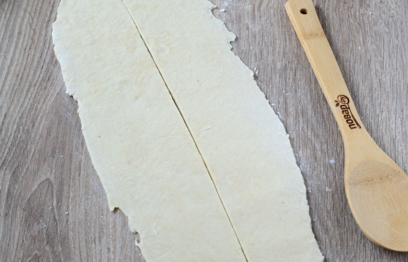 1. Этап. Гокая: Затем раскатайте тесто в форме длинного овала. Разрежьте его пополам. Затем каждую часть сложите снова пополам вдоль и заверните в рулетик.