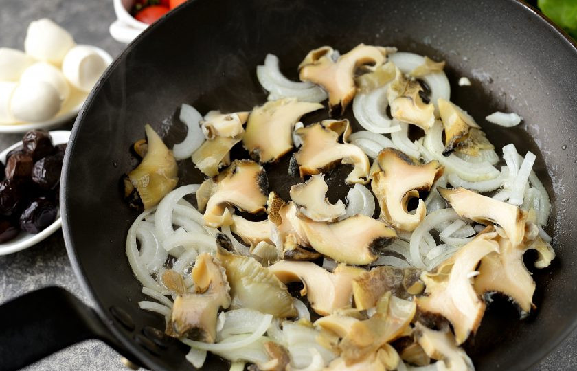 1. Этап. Салат с рапанами: Тонко нарежьте рапаны, выложите в сковороду, жарьте вместе с луком минуты 2, не дольше.