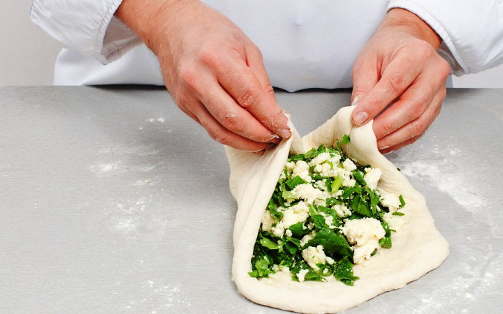 1. Этап. Осетинский пирог в мультиварке: Тесто разделите на 3 части. Каждую часть разомните в тонкую лепешку, выложите часть начинки и соберите края лепешки поверх начинки. Ладонями разомните пирог, придав ему круглую форму по размеру соответствующую диаметру чаши мультиварки.