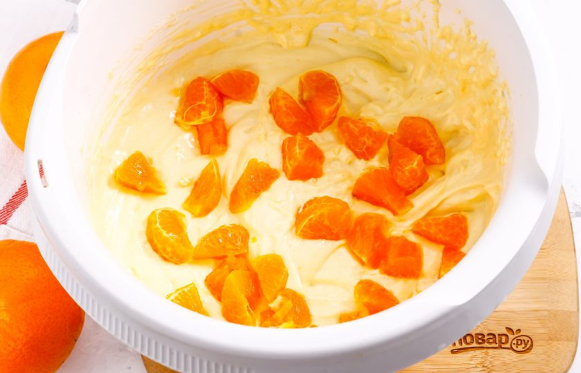 1. Этап. Бисквит с мандаринами: Очистите мандарин от кожуры и белых волокон, разделите плод на дольки. Разрежьте каждую дольку на две части и удалите косточки. Добавьте в тесто и перемешайте. Если будете добавлять 2 мандарина, то нарезку второго выложите на тесто в форме, иначе нарезки опустятся на дно выпечки.