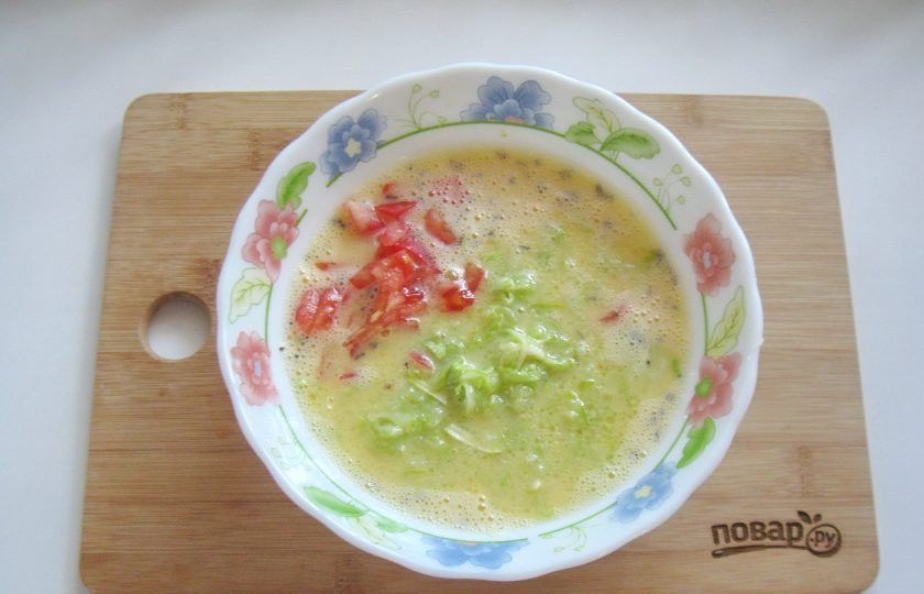 1. Этап. Омлет с сыром и кабачком: Добавьте кабачок и помидор, который предварительно обдайте кипятком, снимите шкурку и мелко нарежьте.