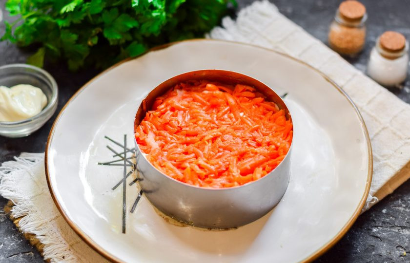 1. Этап. Салат Океан со шпротами: Поверх картофеля выложите натертую на средней терке вареную морковь. Смажьте слой майонезом.