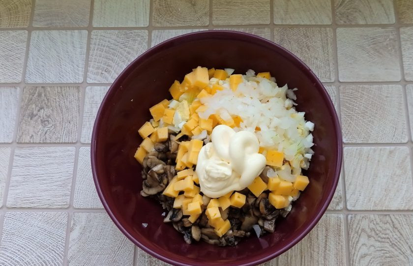 1. Этап. Салат Любимый с курицей и грибами: Репчатый лук очистите, нарежьте мелко и залейте кипятком на 3-5 минут. Слейте воду, а лук выложите в миску. Заправьте салат майонезом, посолите и поперчите по вкусу.