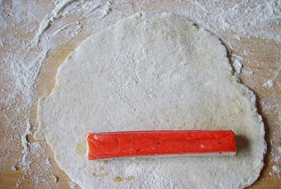 1. Этап. Крабовые палочки в тесте: Кусочек теста раскатайте, на один край положите крабовую палочку.