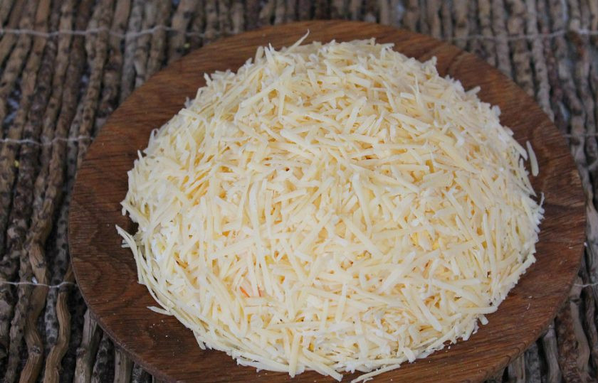 1. Этап. Французский салат на Новый год: Твердый сыр трем на терке и выкладываем завершающим слоем. Выравниваем края.