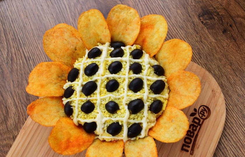 1. Этап. Салат Подсолнух: 8. Перед подачей на верхний слой салата нанесите сетку майонеза, в ячейки – половинки маслин. По краям салат оформите крупными чипсами. Приятного аппетита!