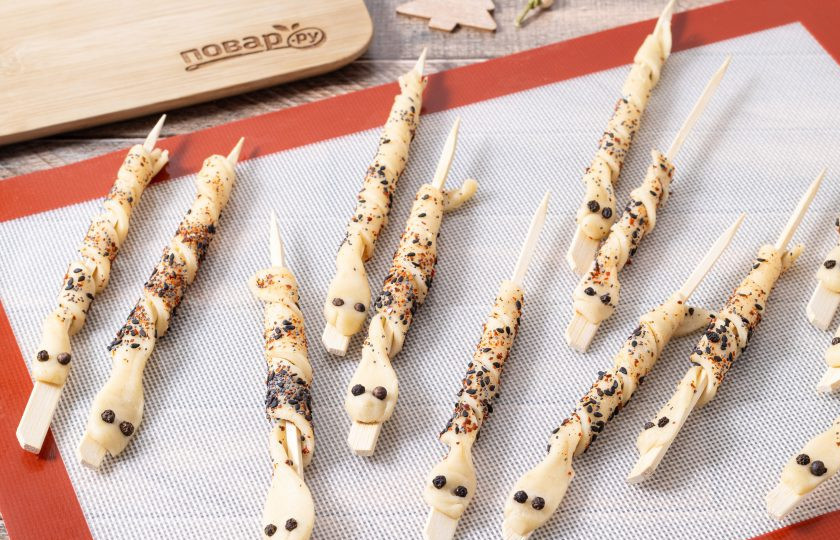 1. Этап. Хлебные палочки «Змейки»: Из края без посылки сформируйте голову змейки и вставьте туда 2 горошины черного перца — это будут глаза. Саму полоску теста намотайте спиралью на шпажку. Выпекайте палочки 15-20 минут в разогретой до 100 градусов духовке.
