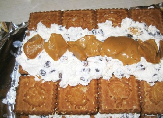 1. Этап. Торт с печеньем и творогом: 6. Оставшийся творог выложите вдоль по центру, а затем — несколько ложек сгущенки.