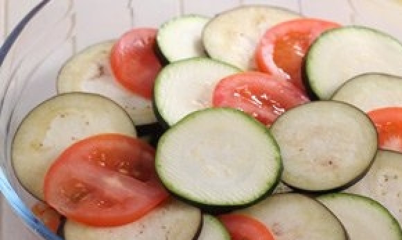 1. Этап. Рататуй в духовке: В жаропрочную форму уложите половину ингредиентов со сковороды. Затем поочерёдно одну часть нарезанных овощей. Вторую половину тушёных овощей и оставшиеся кружки.