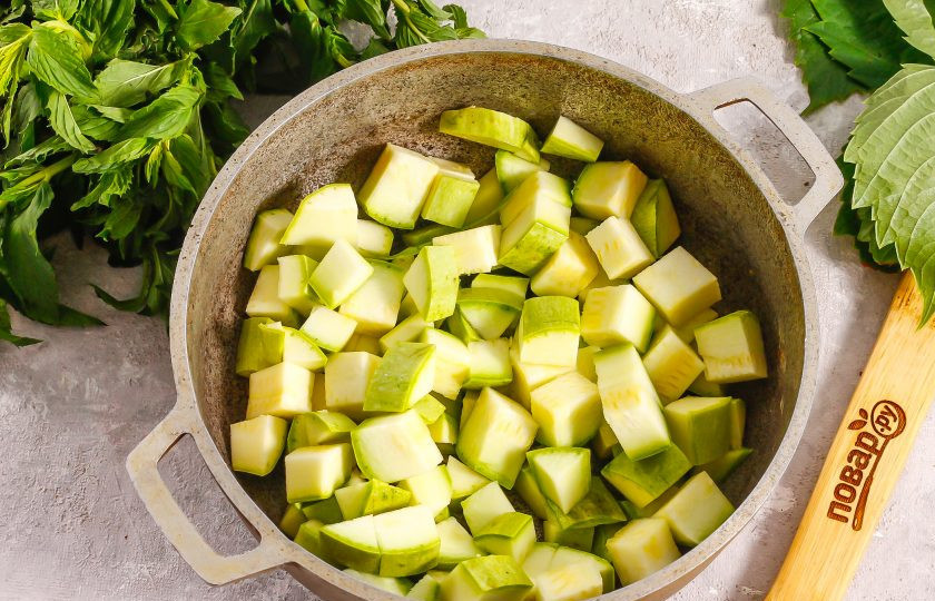1. Этап. Кабачки в персиковом соке на зиму: Кабачки промойте в воде, срежьте с овощей хвостики и нарежьте их небольшими кубиками. Помните, что они уварятся в два раза, поэтому слишком мелко не нарезайте. Пересыпьте нарезку в казан или кастрюлю с антипригарным дном.
