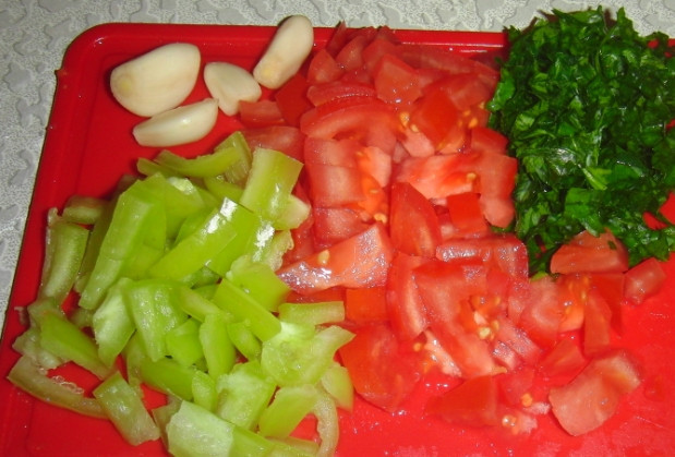 1. Этап. Куриное рагу в тыкве: Нарезаем кубиками помидор и болгарский перец соломкой, мельчим зелень петрушки, головку чеснока чистим до состояния зубчиков, зубчики не режем – они используются целиком.