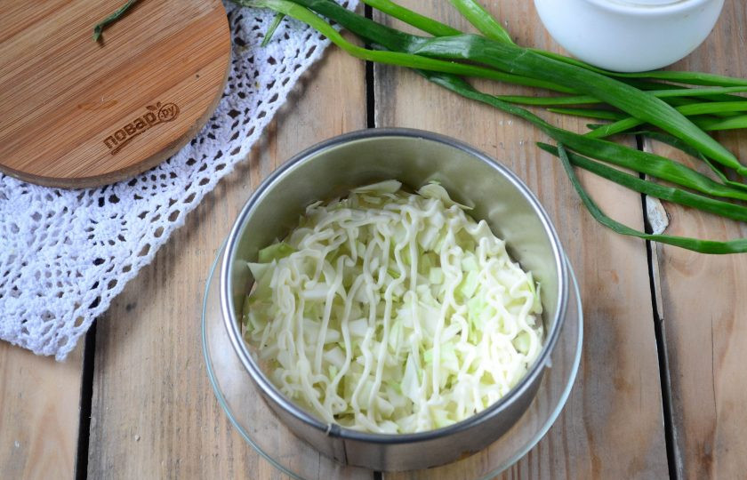 1. Этап. Салат слоеный Рандеву: И сразу начинаем собирать салат. На плоскую тарелку установите сервировочное кольцо или обрезанную бутылку. На дно выложите мелко нарезанную капусту, сверху покройте сеточкой майонеза.