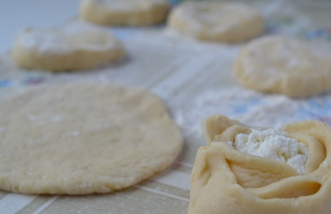 1. Этап. Ватрушка с творогом без дрожжей: 4. Раскатываем тесто, вырезаем равные части круглой формы толщиной около 0,5 см. Делаем углубления, в которые выкладываем нашу начинку, после чего заворачиваем края кверху, формируя розочку.