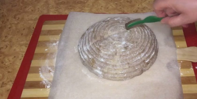 1. Этап. Пшенично-ржаной хлеб на закваске: Присыпьте тесто мукой и оставьте на 2-3 часа. Придерживая тесто рукой, переверните корзинку и выложите на пергамент. Аккуратно смахните кисточкой муку, сделайте несколько надрезов и сбрызните водой.