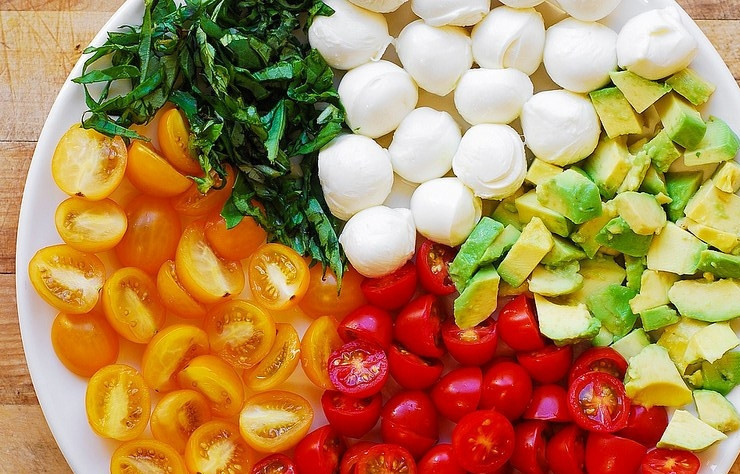 1. Этап. Салат с авокадо и сыром: Нарежьте половинками помидоры. Авокадо нашинкуйте квадратиками, а базилик небольшими кусочками.