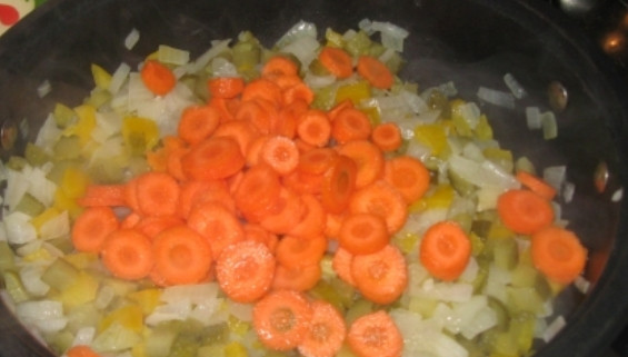 1. Этап. Солянка в горшочках: Теперь добавьте очищенную и порезанную колечками морковь.